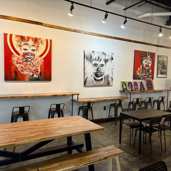 The Taste Smokers restaurant interior with modern art, wooden tables, and black chairs.
