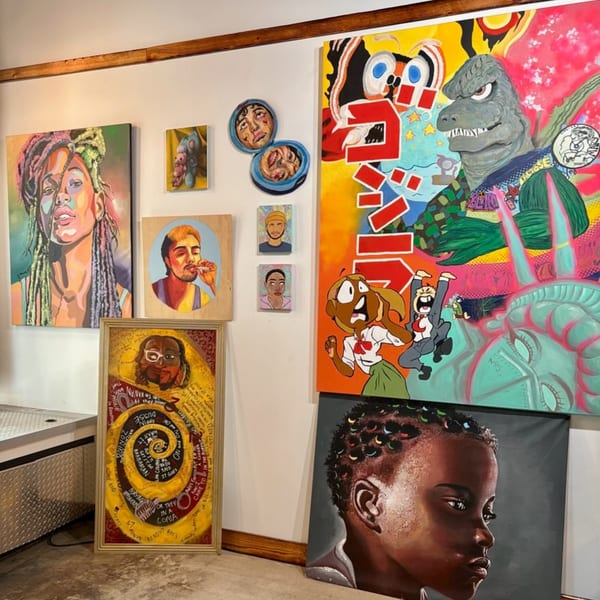 A wall covered with vibrant, diverse paintings, including portraits, abstract art, and pop culture references.